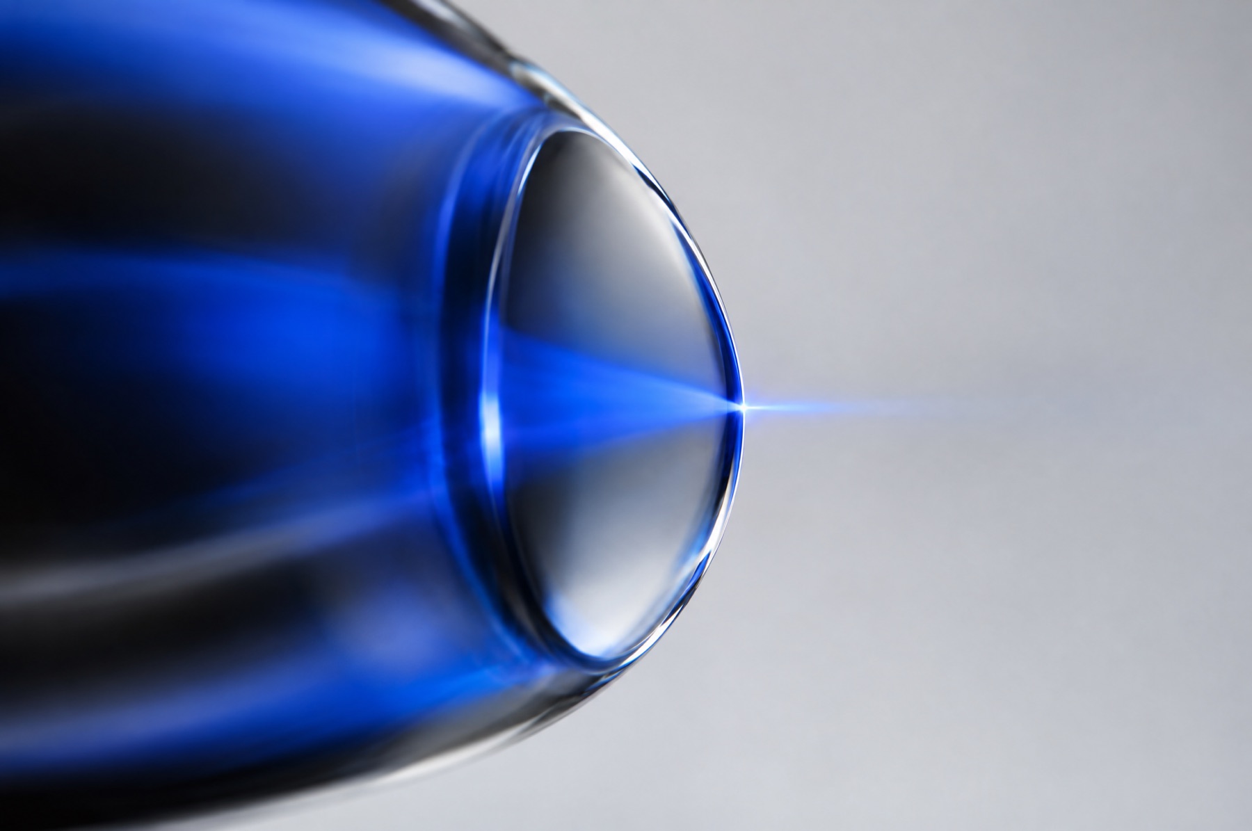 Eine Glaslinse bündelt diffuses blaues Licht in einem scharfen Punkt als Sinnbild für das gezielte Testen eines Brand Voice Prompts.